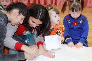 Помощник куратора акции Екатерина Белолипецкая учит девочек рисовать